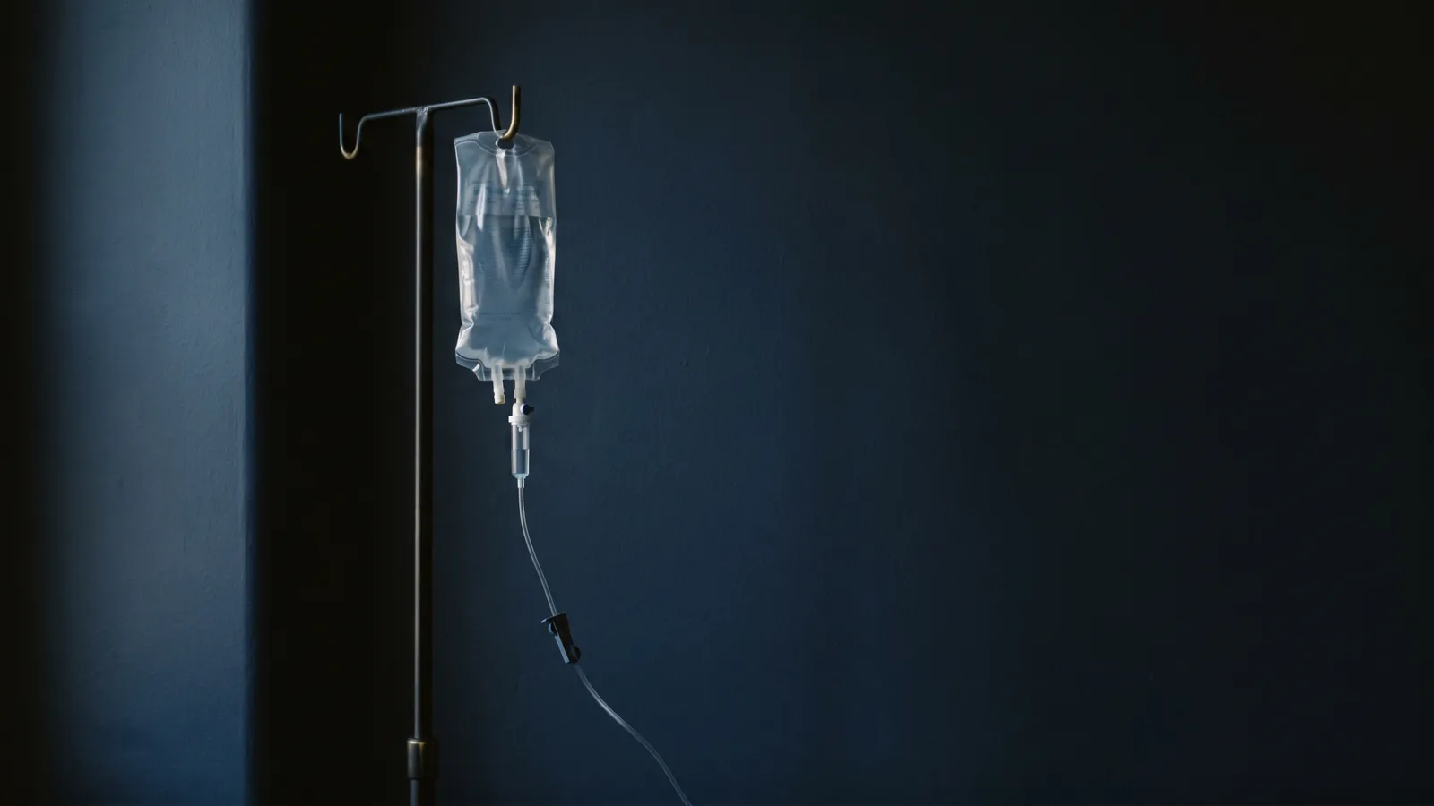 A clear IV infusion bag against deep shadow