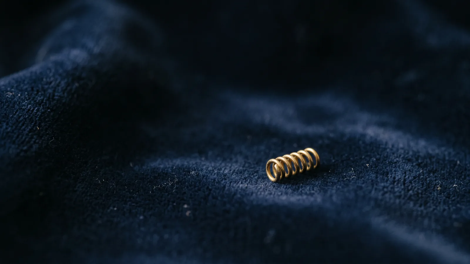 A small spiral surgical marker implant on dark velvet