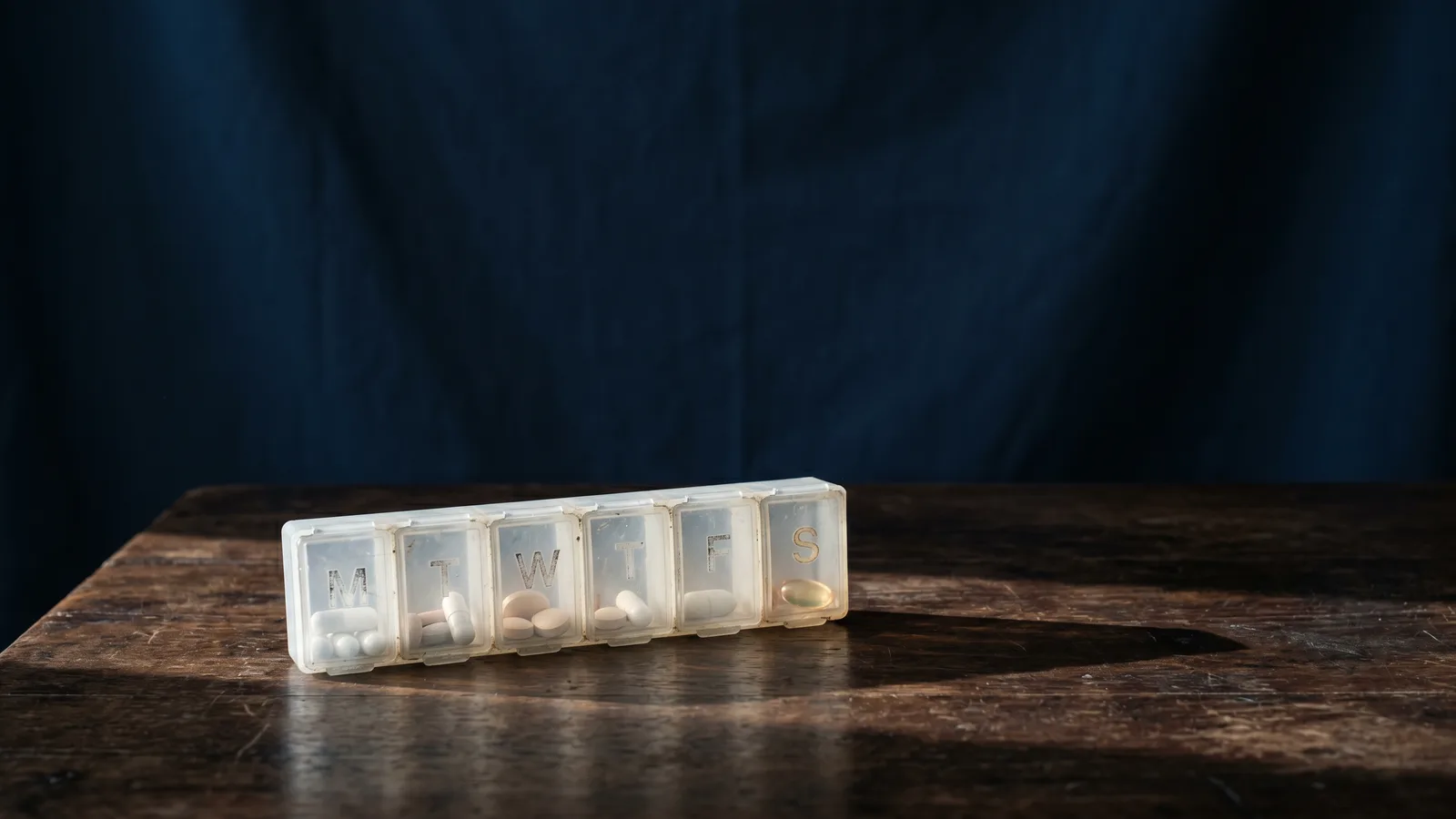 A weekly pill organizer casting long shadows