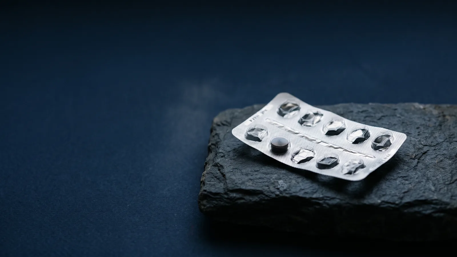 A foil blister pack catching a thin band of light