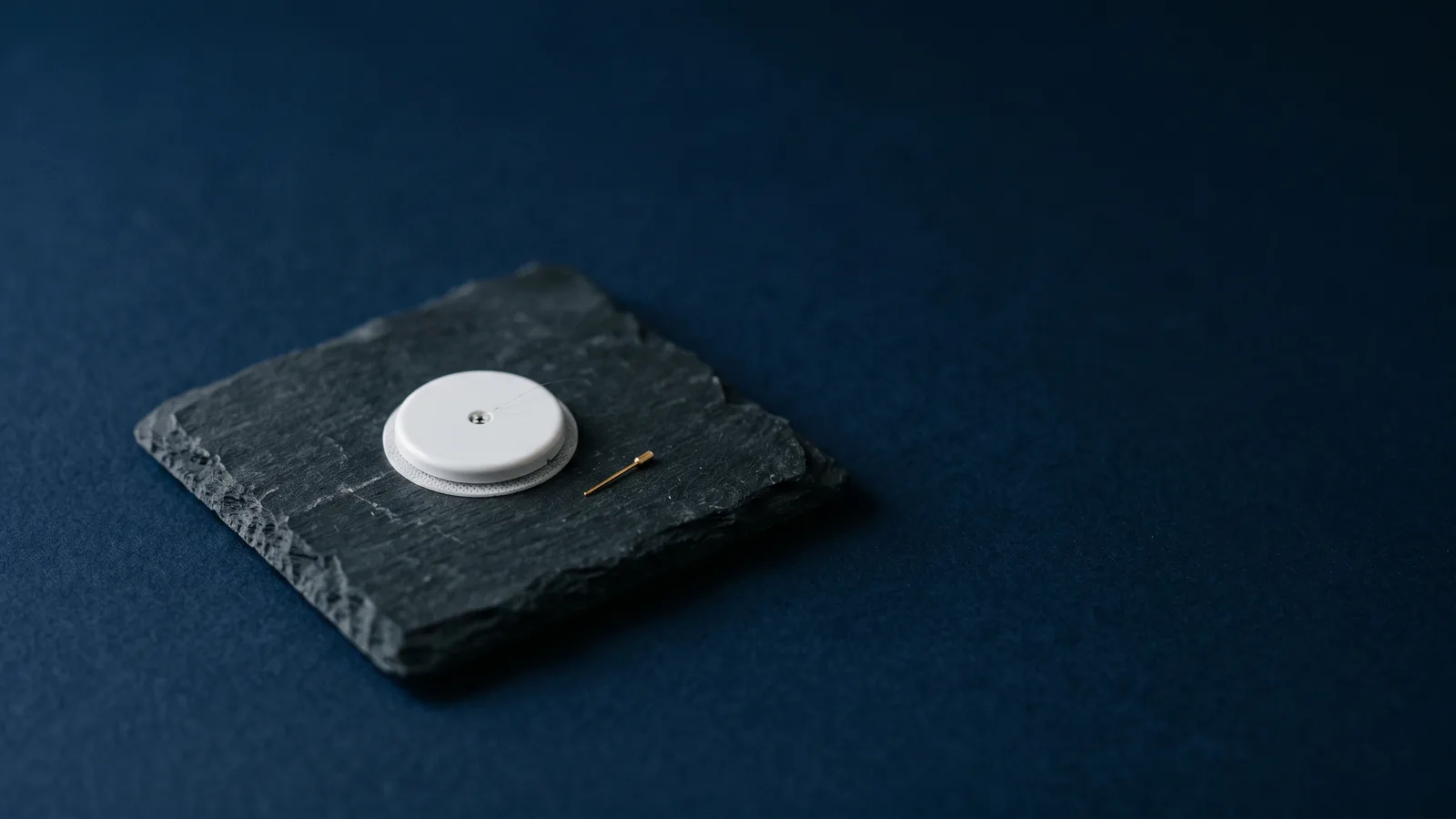 A small circular glucose sensor disc on dark slate