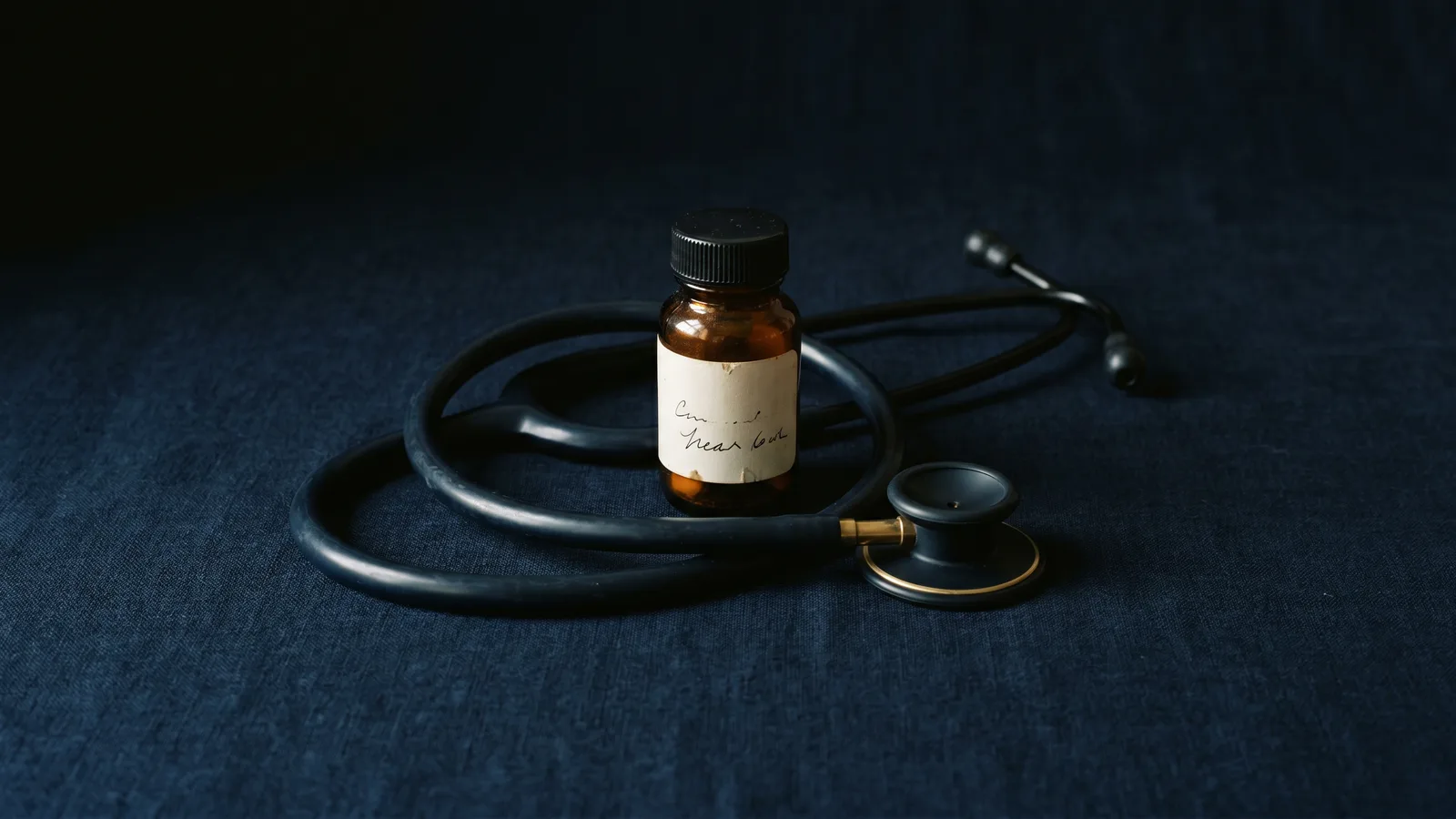 A stethoscope coiled around a small pill bottle