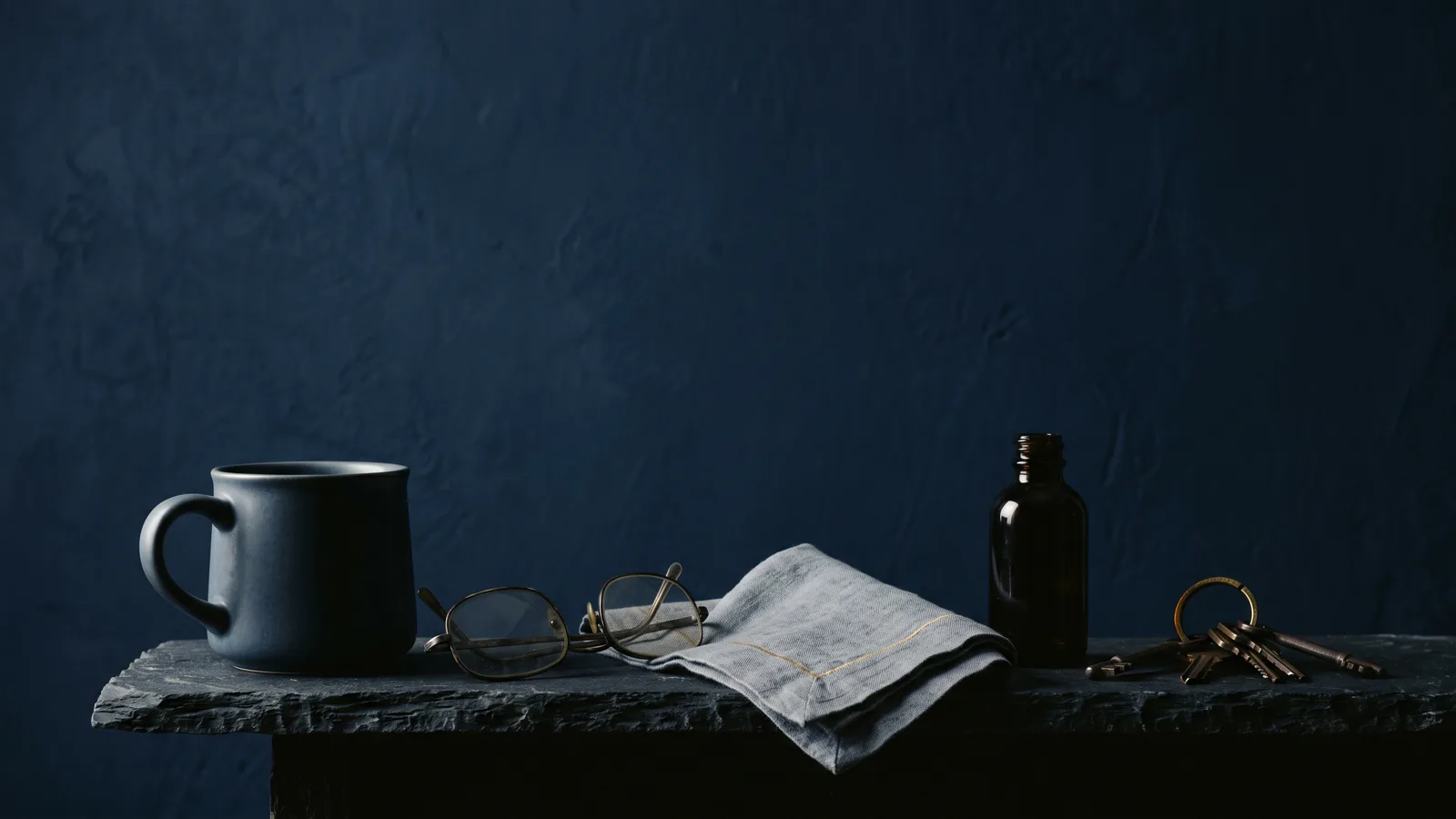 Everyday consumer objects in silhouette on dark stone