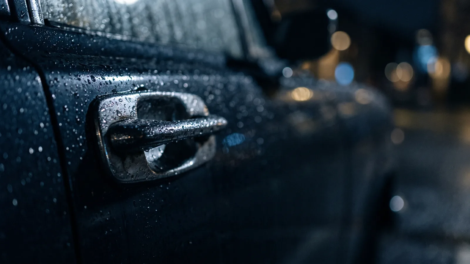 A car door handle in rain at night, shallow depth of field