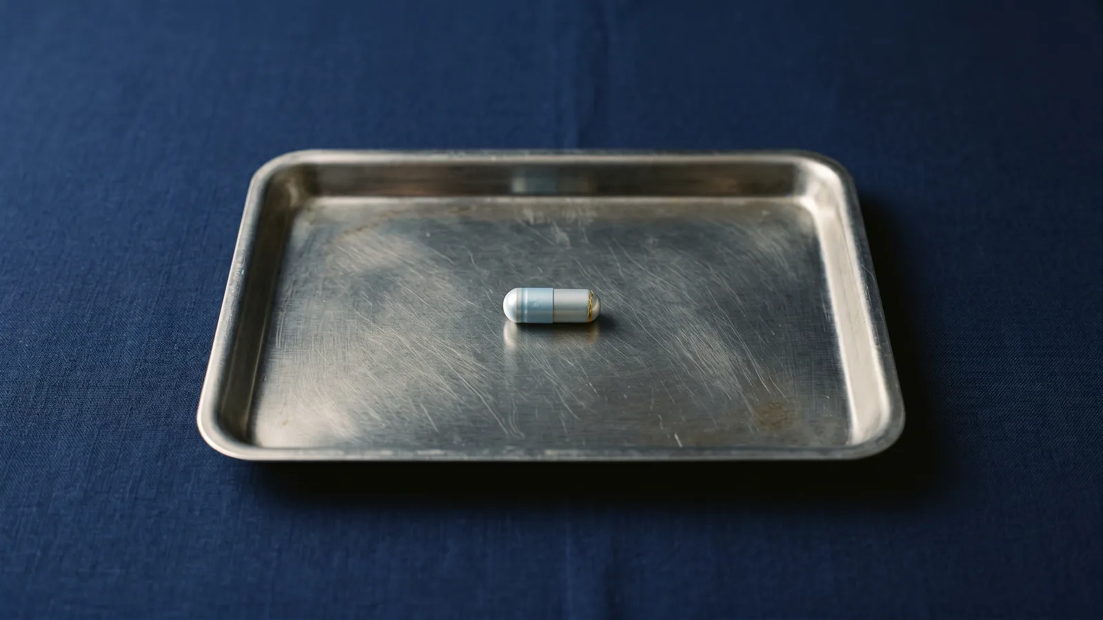 A capsule on a brushed steel laboratory tray