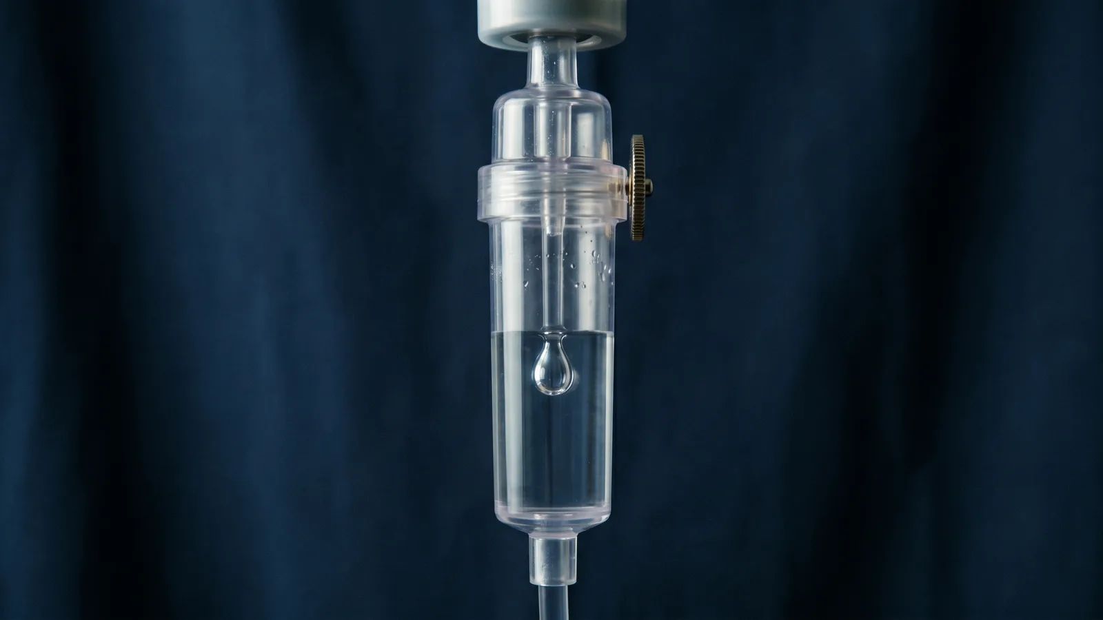 An IV drip chamber in macro with a single suspended drop