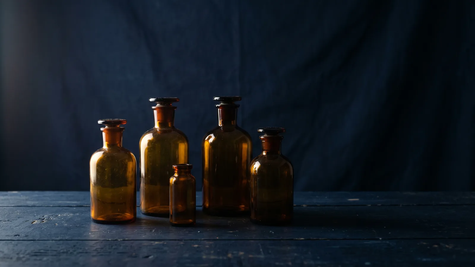 Amber laboratory bottles silhouetted in dramatic side light